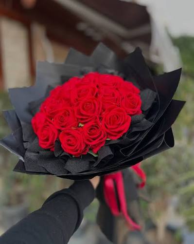 Red roses bouquet in dramatic all-black wrap with pink ribbon